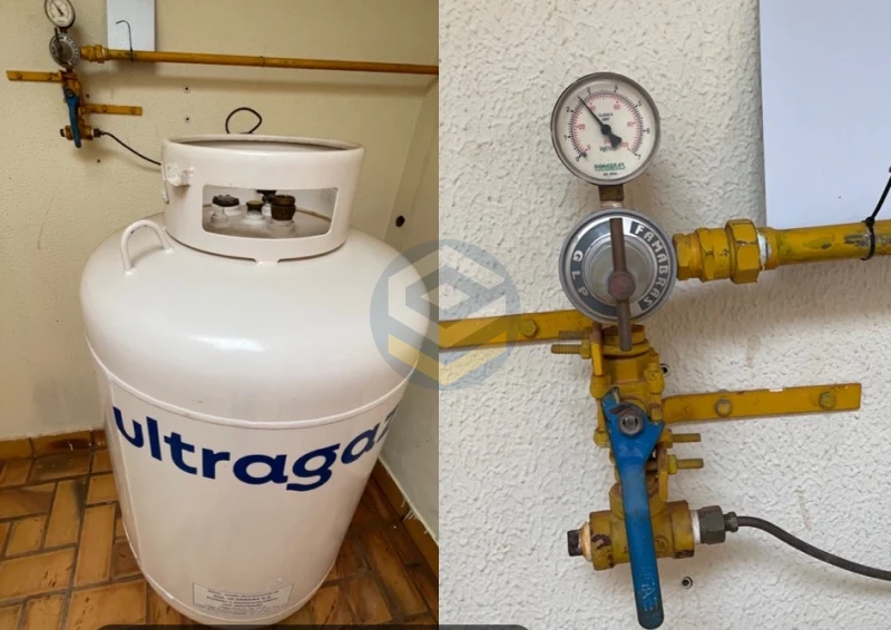Central de gás GLP com botijão P90 e registro de controle com manômetro em instalação predial, utilizada para abastecimento de múltiplos pontos de consumo.