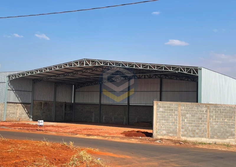 Galpão metálico 30x15m com pilares de perfil acoplado, tesoura metálica com banzo inferior reduzido, frente aberta e fechamento em telha e alvenaria.