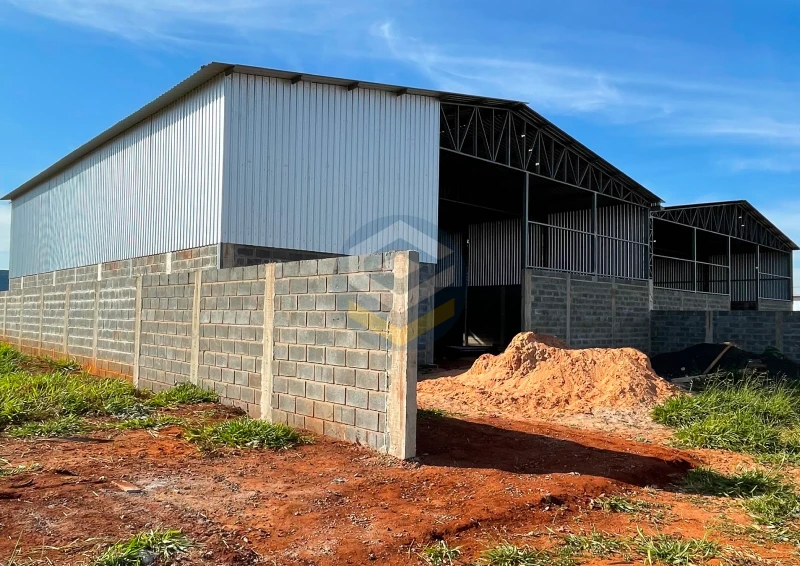 Galpão metálico geminado com dois módulos de 18x20m, compartilhando pilar central e fechamento em telha e alvenaria.